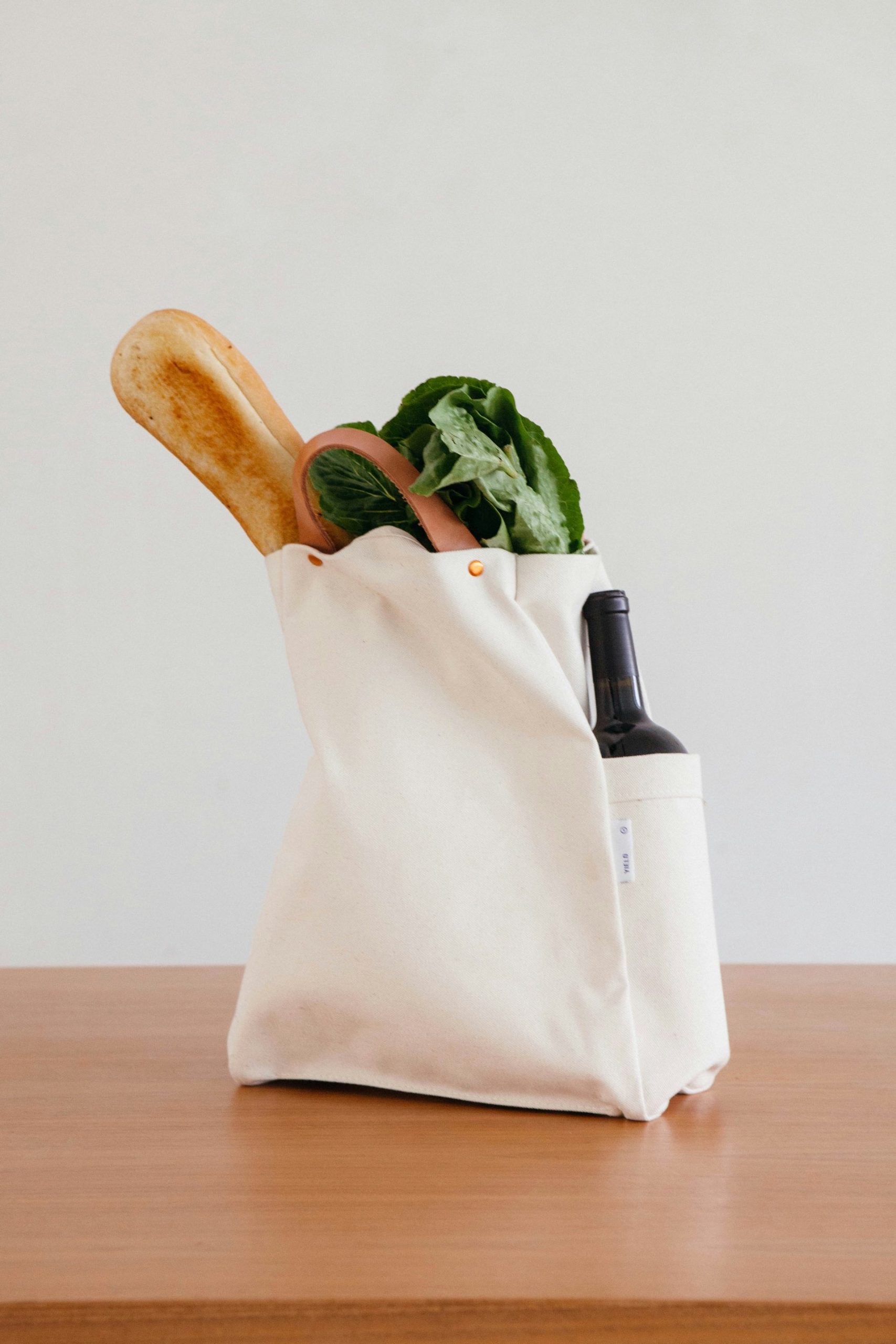 Canvas bag full of vegetables, a baguette, and wine